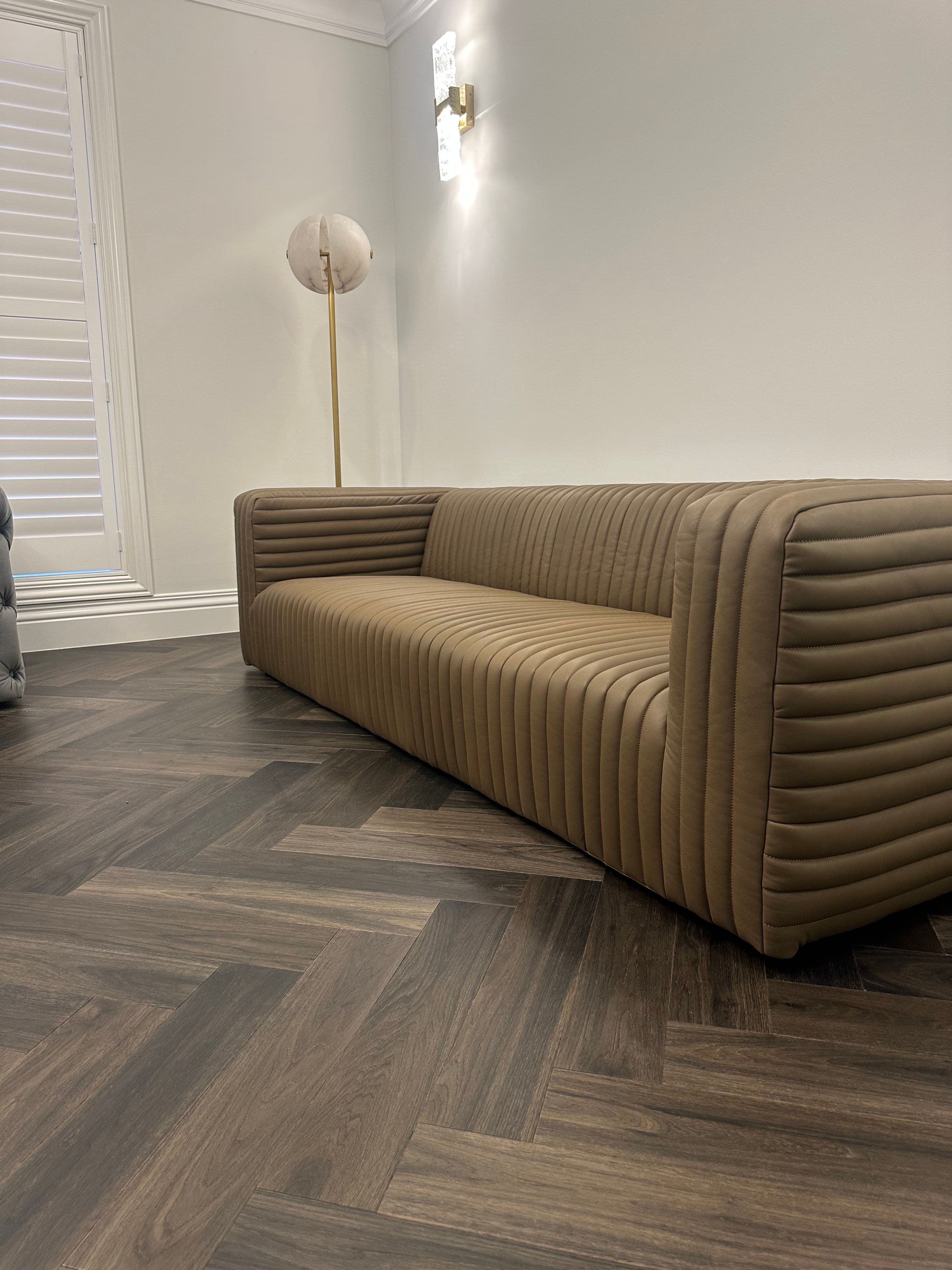 Ash Grey herringbone flooring beside a curved sofa in a Camberwell living room.