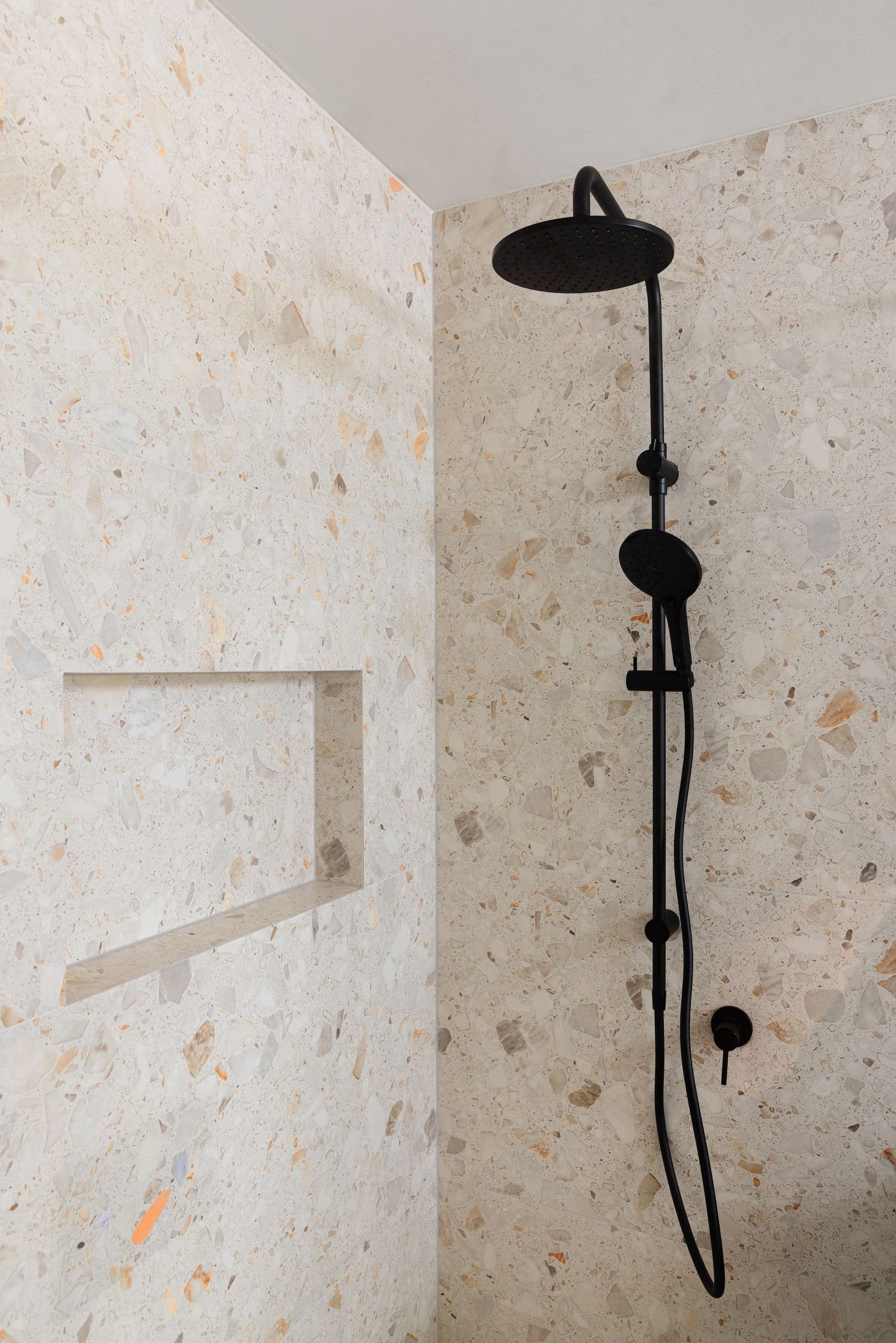 Black shower fixture against stone tiles in Wheelers Hill.